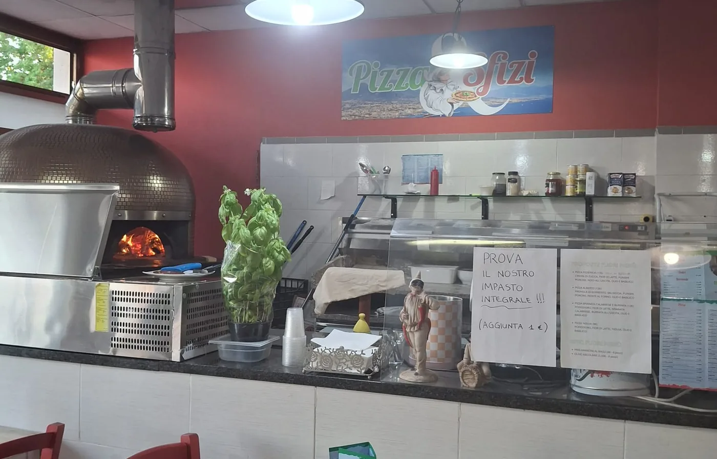 Il forno e il banco di Pizza & Sfizi, con l'insegna del locale sulla parete rossa