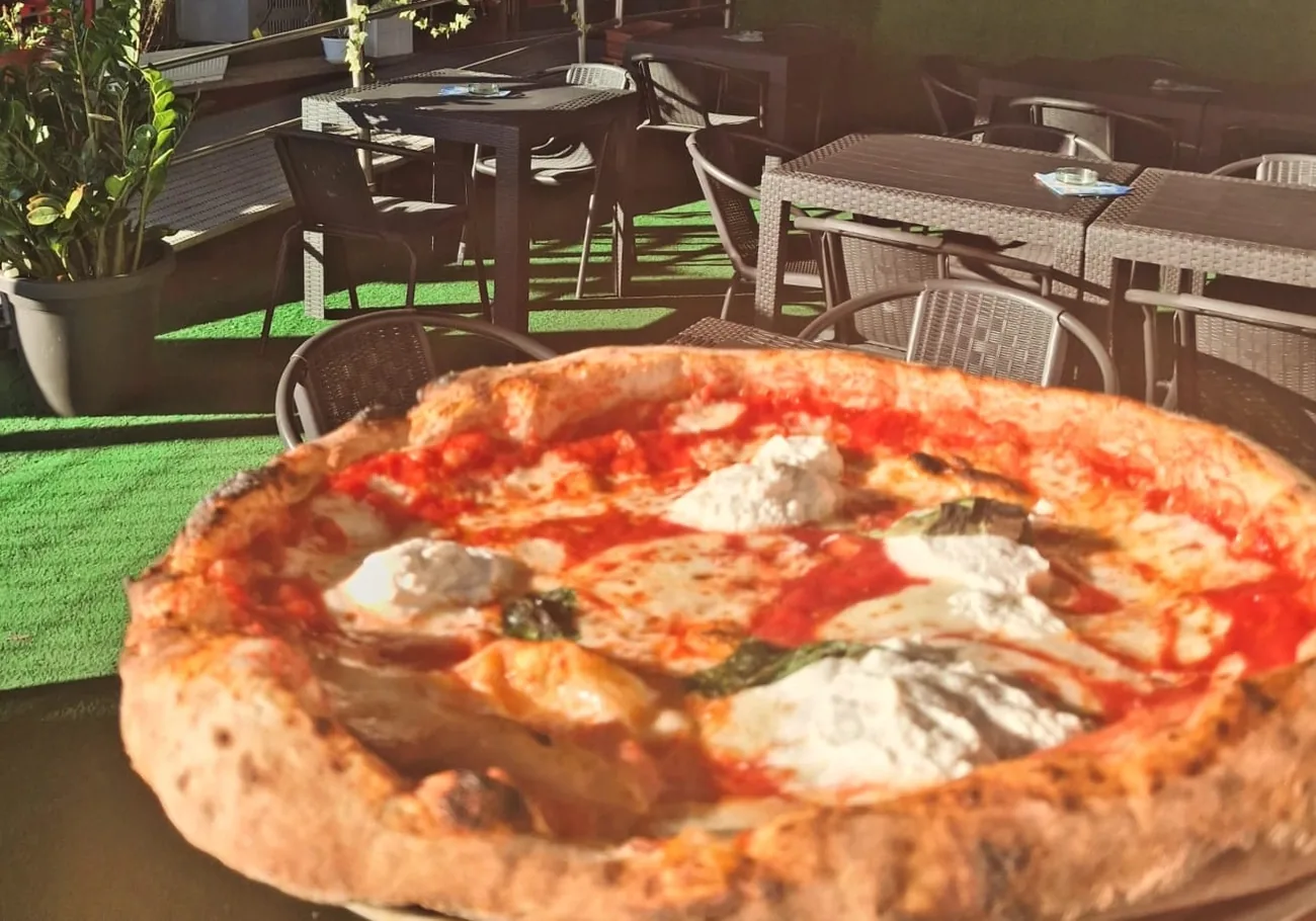 Una pizza con pomodoro, bufala e basilico appena servita sulla terrazza