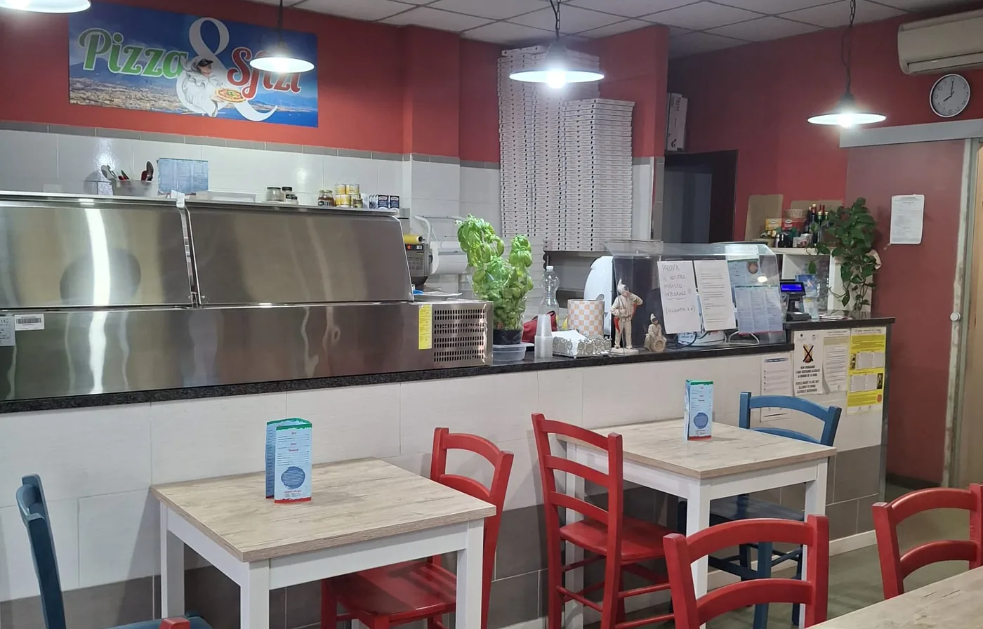 La sala di Pizza & Sfizi con i tavoli, il banco e l'insegna sulla parete rossa